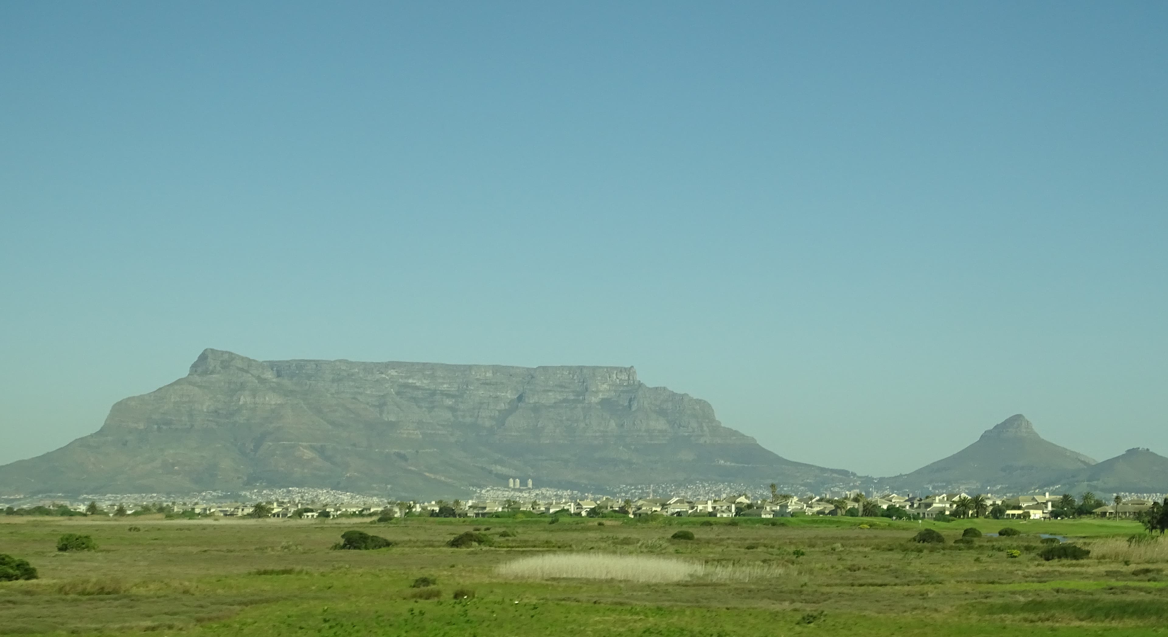 Flat-topped Table Mountain towering over Cape Town city and coastline under clear sky