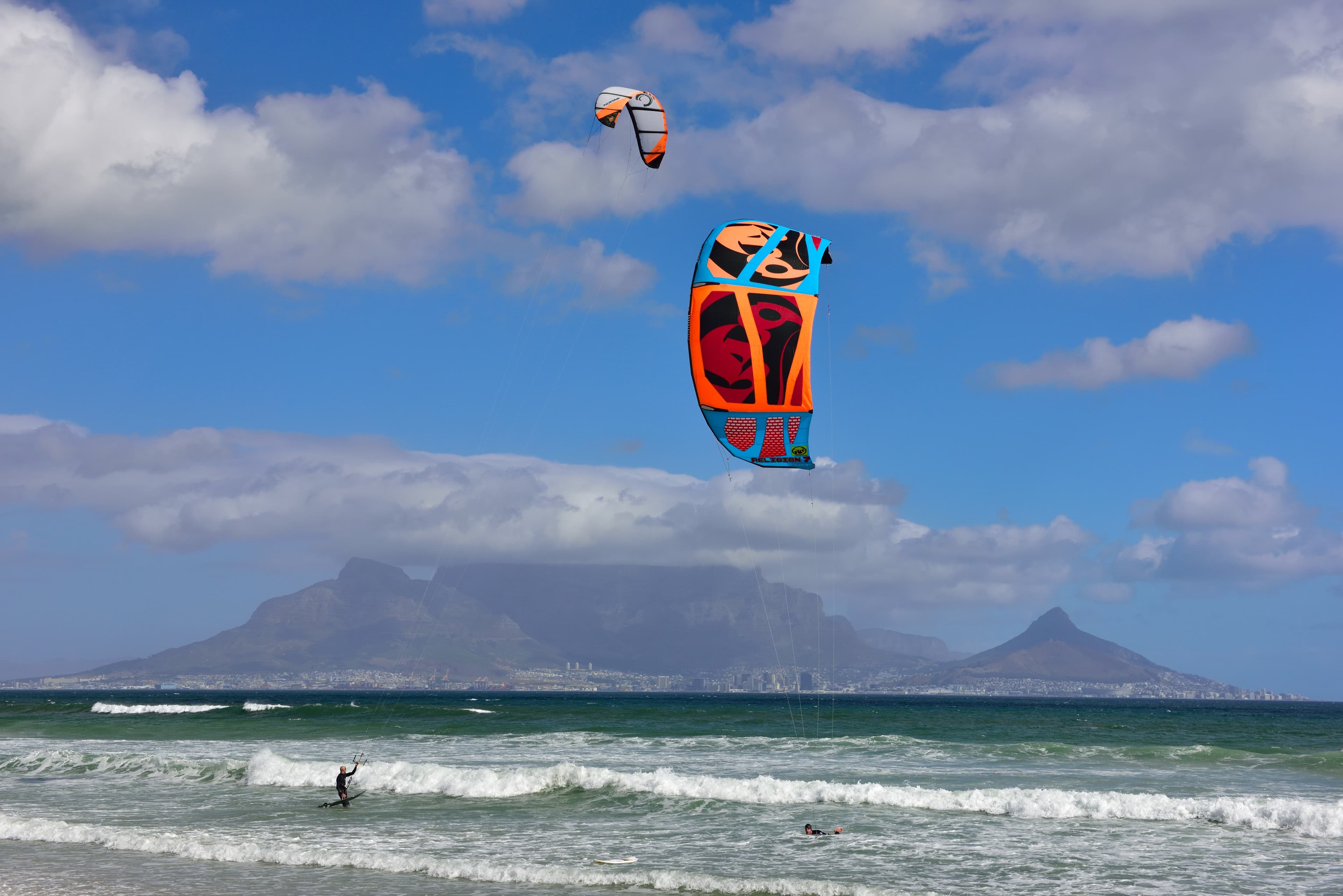 从开普敦 Bloubergstrand 海滩越过桌湾远眺桌山,近岸浪花翻卷